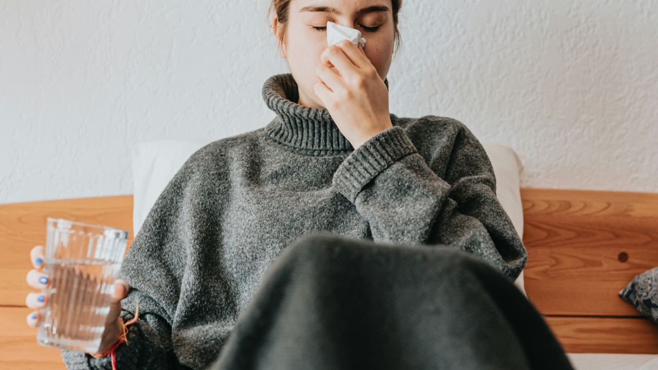 woman sneezing in a gray blanket